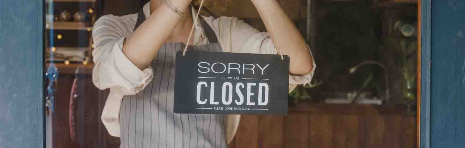 Business owner holding a closed sign.